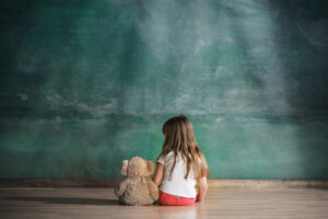 brown teddy bear | child therapy in Baltimore, MD | play therapy in Baltimore, MD | Baltimore child therapist | children's therapy in Maryland | 21042 | 21043 | 21228 Image of a girl with a teddy bear sitting in front of a chalk board. Showing how a kid can feel isolated without children's therapy in Maryland. We use play therapy with toys such as the bear as part of our child therapy in the Washington DC area and Baltimore, MD.
