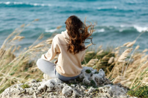 Image of person finding peace by sitting and looking out at the ocean. Representing the peace you can find from counseling and therapy for women in Washington D.C, Baltimore, & Columbia. A therapist for women can help you find a way to find calmness like this.