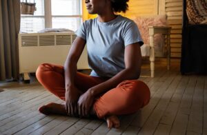 Image of a woman sitting on the floor practicing mindfulness. Showing what to do for depression in. Along with mindfulness for depression help you can also try depression treatment in Baltimore, MD.