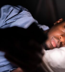 Image of a adolescent boy laying in bed staring at his phone. Showing one of the stressors that a therapist for teens in Columbia or Baltimore, MD can help with. Through counseling for teens in the Washington D.C. area you can give them support as they navigate becoming an adult.